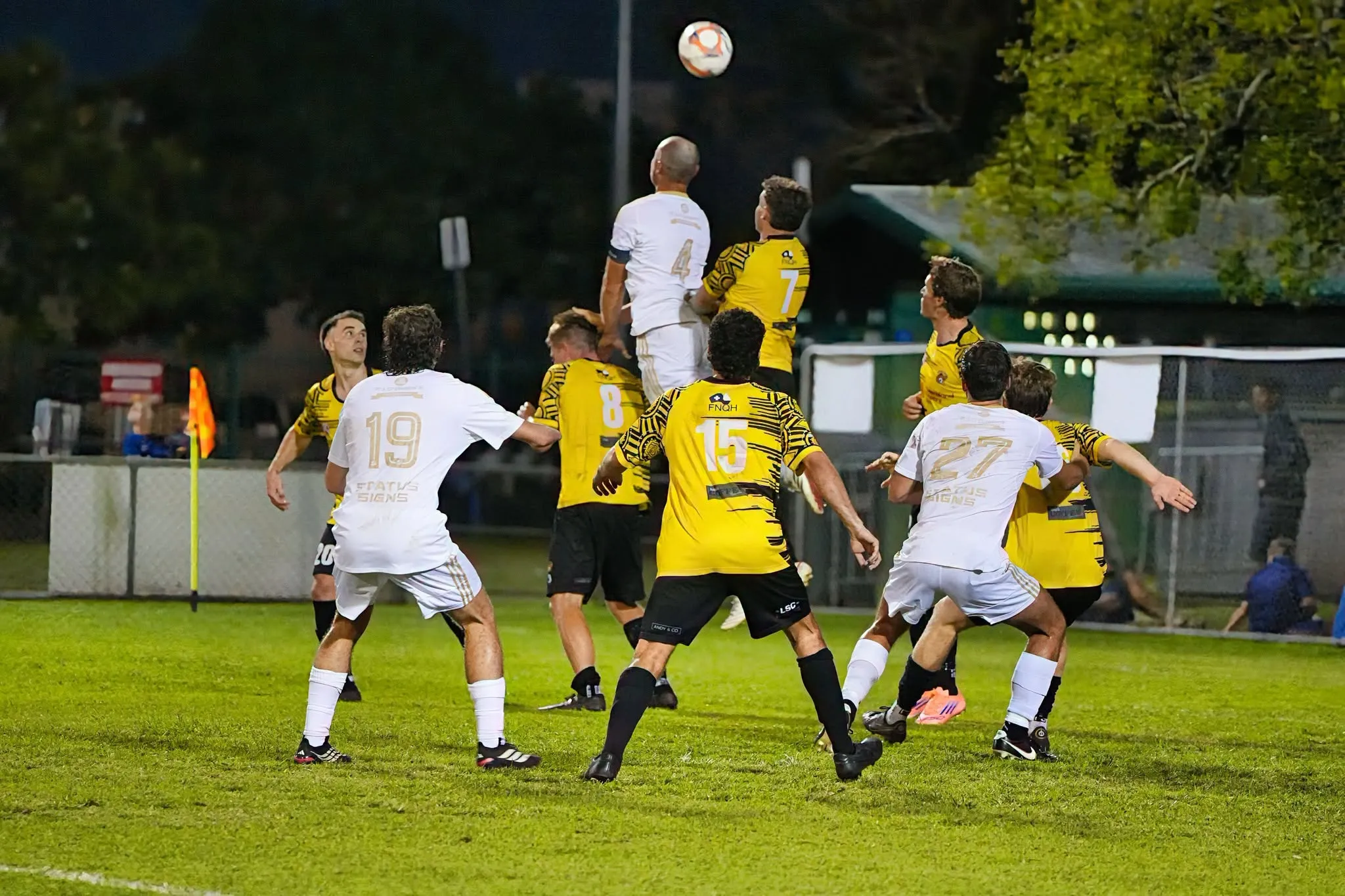 Marlin Coast Rangers senior players contesting a high ball from a set piece under lights