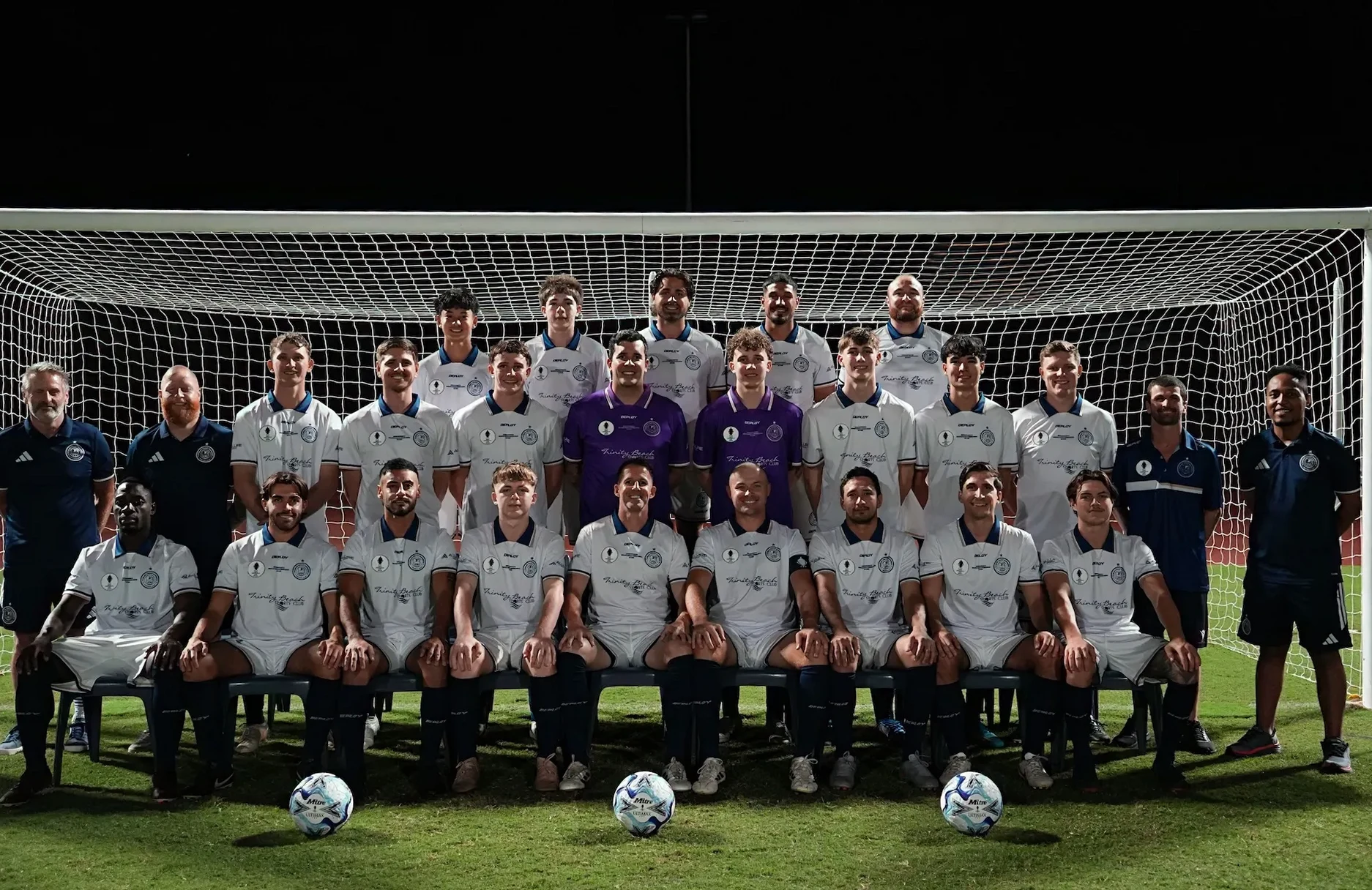 Marlin Coast Rangers senior squad and coaches posed in front of the goal under lights at Pennell Field